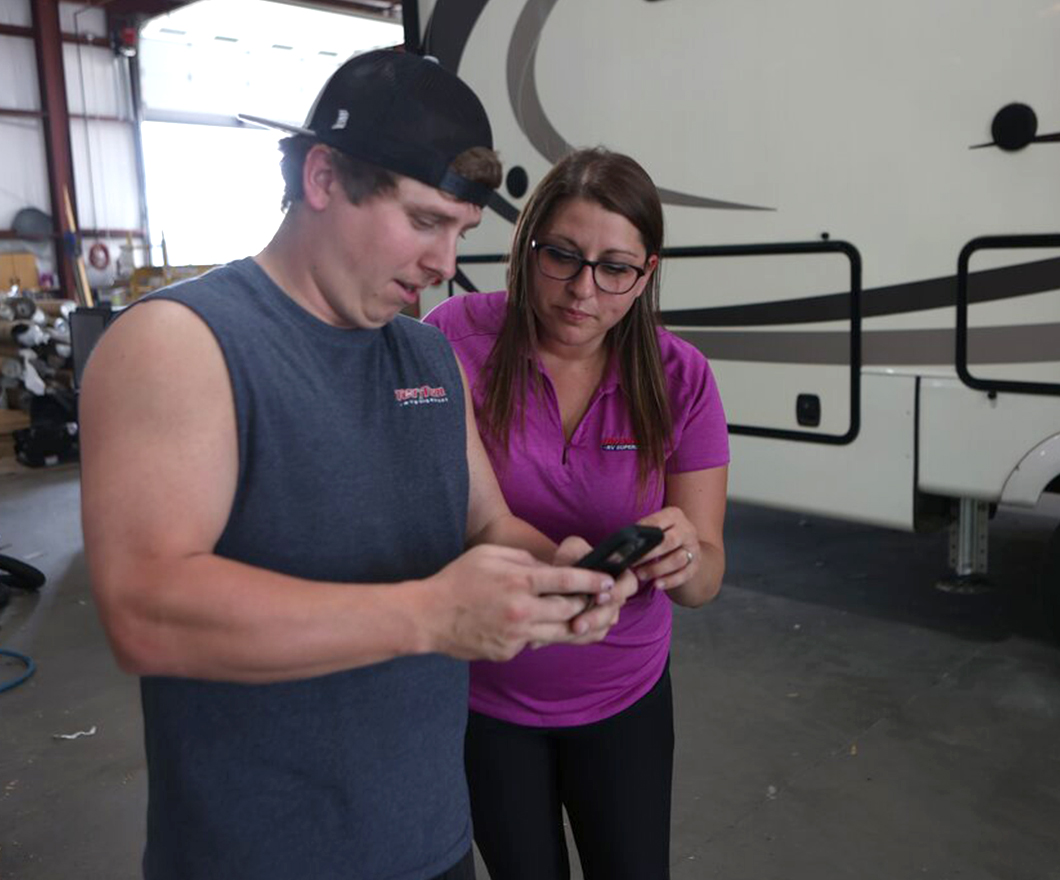 RV service technicians working on mobile device.