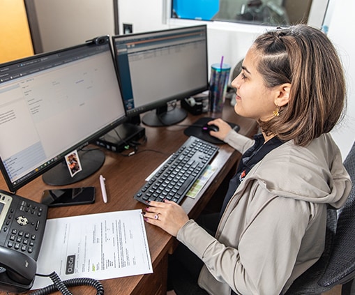 Woman working in front of two computer monitors at a desk