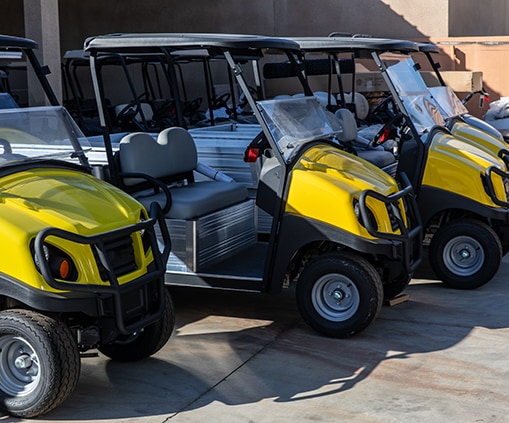 Several yellow golf carts parked in front of a building